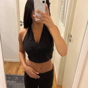 Svart och vit croppad halterneck topp - Två croppade halterneck-toppar i svart och vitt med djup v-ringning och knyt i ryggen. Snygg passform som framhäver axlarna och öppen rygg. Skriv om ni vill köpa separat.