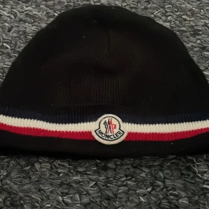 Svart Moncler mössa med ränder - Helt ny, kan byta men kan sälja också, pris kan diskuteras.