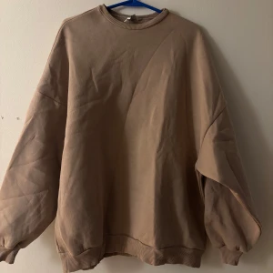 Beige oversized sweatshirt NLY Trend - Beige oversized sweatshirt från NLY Trend med rund halsringning och breda muddar vid ärmslut och nederkant. Tröjan har en loose passform och är tillverkad i mjuk bomullsblandning, perfekt för chill dagar.