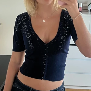 Mörkblå topp med paljetter - Mörkblå finstickad topp från atmosphere med paljettdetaljer och knappar. Går både att bära som den är och ha den som en kofta med ett linne under💗