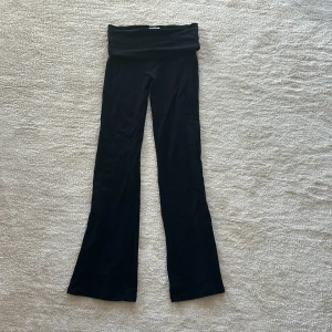 Svarta yoga pants från Gina Tricot - Svarta yoga pants från Gina Tricot med stretchigt material. Byxorna har en bred linning som kan vikas ner och är tillverkade i mjuk bomullsblandning. Perfekta för en avslappnad och trendig look. Storlek 146-154
