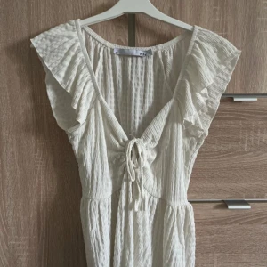 Vit topp  med volang och knyt - Superfin vit topp från Lager 157 med volangdetaljer vid axlarna och snygg knytning framtill. 