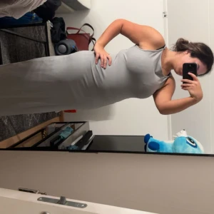 Grå långklänning med smala axelband - Säljer en stilren grå långklänning med smala axelband och rundad halsringning. Klänningen har en tight passform som framhäver figuren och är tillverkad i ett mjukt, stretchigt material. Perfekt för dig som gillar minimalistisk och clean stil.