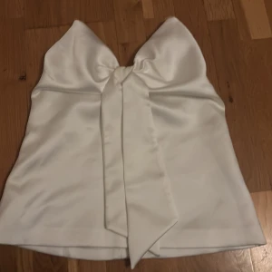 Vit satin bandeau topp med rosett - Supersöt vit bandeau topp i satin med stor rosett i fram💕Inga defekter💕Toppen är endast använd vid ett tillfälle💕
