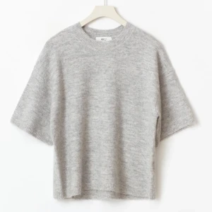 Grå stickad kortärmad tröja - Mysig grå stickad tröja från Other Stories med korta ärmar och avslappnad passform. Tröjan har rund halsringning och är tillverkad i ett mjukt material som passar perfekt för lager-på-lager-stil under kyliga dagar.