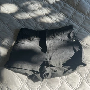 Svarta jeansshorts från FB Sister - Snygga svarta jeansshorts från FB Sister i storlek M. Modellen är högmidjad med klassiska fem fickor och knapp- samt dragkedja framtill. Materialet är jeans med lite stretch och shortsen har råa kanter nedtill för en cool vibe.