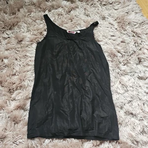 Svart linnetopp från Indiska - En enkel och stilren svart linnetopp från Indiska i storlek M. Toppen är ärmlös med klassisk rund halsringning och tillverkad i ett tunt, lätt material som känns skönt mot huden. Perfekt att matcha med jeans eller kjol för en clean look.