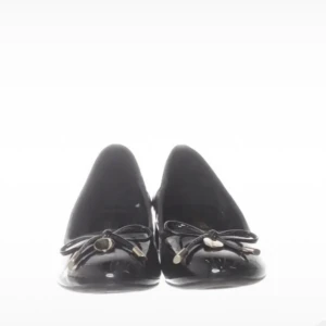 Svarta ballerinaskor med rosett - Svarta ballerinaskor i lack med rund tå och låg klack. Framtill sitter en dekorativ rosett med guld detaljer. Köpta på Sellpy men aldrig använda av mig för de dessvärre är för stora.