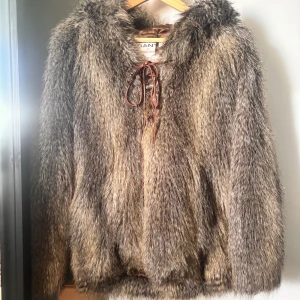 Brun pälsjacka från GANT - Säljer en fluffig och lyxig brun pälsjacka från GANT by Michael Bastian. Jackan har huva, snörning framtill och är tillverkad i pälsmaterial med snygga färgskiftningar i brunt och beige. Perfekt för dig som vill sticka ut med en statementjacka i vinter.