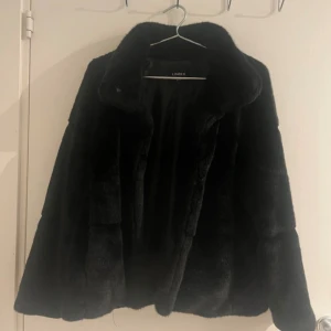 Kortare pälsjacka - Kortare pälsjacka från Lindex. Mycket fint skick, har bara en mindre slitning på höger axel, i form av att pälsen blivit lite förändrad (inga hål och inget som påverkar jackan, se bild).