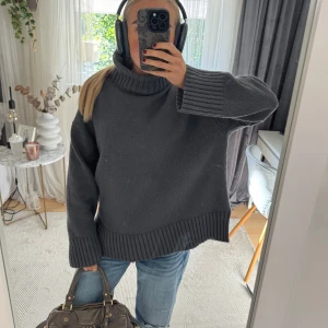 Mörkgrå stickad polotröja - Mysig mörkgrå stickad polotröja med oversized passform och bred ribbad kant vid ärmslut, nederkant och krage. Perfekt för lager-på-lager och chill höst- och vinterstil. Snygg att matcha med jeans eller kjol. Passar xs-m