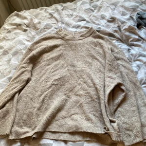 Beige stickad tröja från 157 - Mysig beige stickad tröja från 157 med rund halsringning och ribbade muddar. Perfekt för lager-på-lager och chill dagar. Enkel och stilren design som funkar till allt.