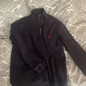 Mörkblå half zip från Polo Ralph Lauren - Mörkblå långärmad tröja från Polo Ralph Lauren med klassisk röd broderad logga på bröstet. Tröjan har en snygg half zip-dragkedja och stårkrage. Perfekt för lager-på-lager och chill stil. Pris går mycket väl att diskuteras!