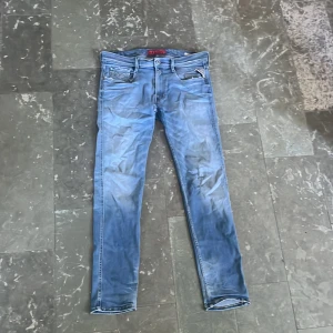 Replay Anbass ljusblå jeans 32/32 - Säljer ett par Replay Anbass jeans i ljusblå tvätt med klassiska och snygga slitningar. Jeansen har normal passform och raka ben, med Replay-logga på fickan och läderpatch bak i midjan. Perfekta för dig som gillar en avslappnad men stilren look. Mycket bra kvalité och skick men säljer billigt då jag växt ur och använder ej. Vid frågor eller funderingar är det bara att höra av sig :)