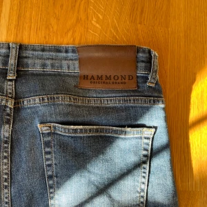Jeans med snygga slutningar - Säljer ett par blå jeans från Hammond med snygga slitningar. Jeansen har klassisk femficksdesign, normal passform storlek 31. Perfekta för dig som gillar jeans med najs slitningar nu till hösten.