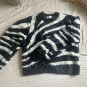 Zebramönstrad fluffig tröja Ivyrevel - Säljer en supermjuk och fluffig zebramönstrad tröja från Ivyrevel. Tröjan är svart och vit med lång ärm och har en riktigt cozy vibe. Perfekt för dig som vill sticka ut med ett djurmönster och älskar att mysa in dig i något riktigt gosigt.
