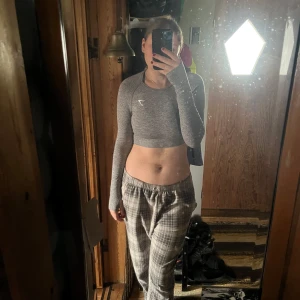 Grå croppad långärmad topp Gymshark - Säljer en grå croppad långärmad topp från Gymshark. Toppen har en tight passform och är tillverkad i ett stretchigt syntetmaterial som passar perfekt till träning. Diskret logga på bröstet och rund halsringning. Jag har klippt bort lappen då jag tyckte den skavde de fåtal gångerna jag använde den