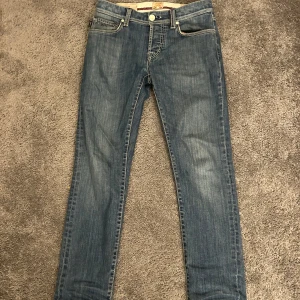 Tramarossa blå jeans straight fit - Snygga blå jeans från Tramarossa, tillverkade i Italien. Klassisk femficksmodell med raka ben och diskreta slitningar. Silverfärgade knappar med saxmotiv och broderad text på insidan. Innerfoder med röda detaljer och märkning 'Made in Veneto'.