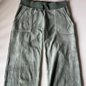 Mintgröna mjukisbyxor Juicy Couture XS - Supermjuka mintgröna mjukisbyxor från Juicy Couture med bred resår och snörning i midjan. Byxorna har två stora fickor framtill och broderad JC-logga på ena fickan.