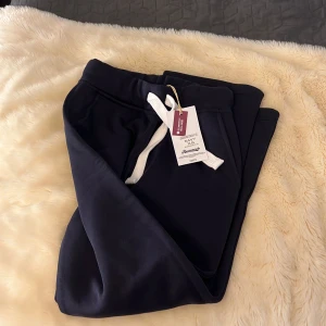 Mörkblå mjukisbyxor med snörning - Mörkblå mjukisbyxor från Russemerch med vit snörning i midjan och bekväma sidofickor. Perfekta för chill dagar eller när du vill ha en avslappnad stil. Klassisk passform och mjukt material. Helt oanvända och it testade. Säljer för fick 2 par i födelsedagspresent! Pris kan diskuteras!