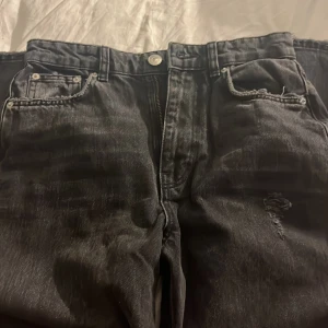 Svarta slitna jeans från Gina Tricot - Svarta jeans från Gina Tricot i storlek 36 med snygga slitningar och hål på båda knäna. Modellen är rak! Hör av er vid frågor/intresse💕