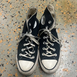 Svarta Converse  - Klassiska svarta Converse med vit sula och tå, vita snören och det ikoniska logomärket på sidan. Perfekta för en avslappnad och cool stil. Använt få gånger i storlek 37