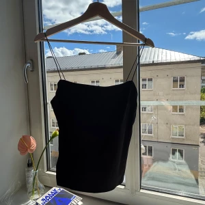 Svart linnetopp från Vanessa Moe - Säljer en svart linnetopp från Vanessa Moe med tunna axelband och rak halsringning. Toppen har en stilren och minimalistisk design som är enkel att matcha. Perfekt för dig som gillar en clean och klassisk look. Använd en säsong! 