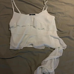 Ljusgrön omlott linnetopp med volang - Superfin ljusgrön linnetopp från Gina Tricot med tunna axelband och snygga volangdetaljer. Toppen har omlottkänsla och är tillverkad i ett lätt, luftigt material som ger en flowy look. Perfekt för varma dagar och somriga outfits.