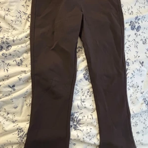 Bruna bootcut byxor från Gina Tricot XS - Snygga bruna byxor från Gina Tricot i bootcut-modell. Byxorna har två bakfickor med lock och knapp, och är tillverkade i ett mjukt bomullsmaterial. Perfekta för dig som gillar en klassisk men trendig look.