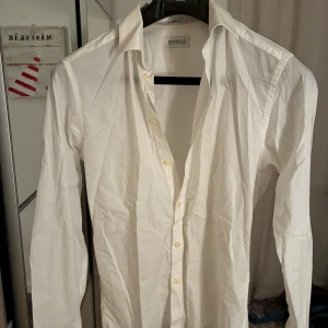 Vit skjorta från These Glory Days - Klassisk vit skjorta från These Glory Days i slim fit-modell. Skjortan har långa ärmar, knappar framtill och en stilren krage. Perfekt för dig som gillar en clean och tidlös look. Nypris cirka 400kr.