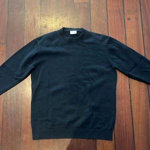 Mörkblå stickad tröja John Henric - Säljer en stilren mörkblå stickad tröja från John Henric. Tröjan har rund halsringning och ribbade muddar vid ärmslut och nederkant. Perfekt för lager-på-lager och funkar året runt. Klassisk och enkel design som passar till det mesta.
