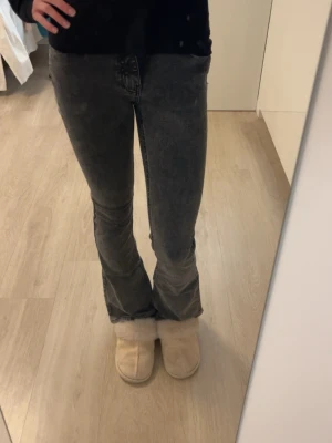 Grå bootcut jeans - Snygga grå jeans med bootcut-modell och lätt tvättad look. Jeansen har klassiska fem fickor och normal passform. Perfekta för dig som gillar en avslappnad men trendig stil.