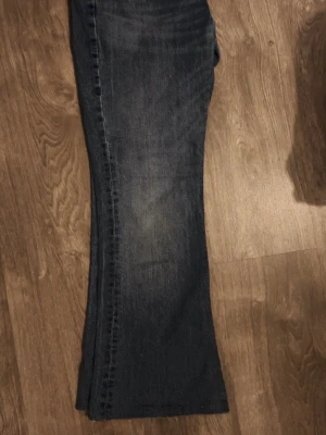 Blå bootcut jeans från Levis - Snygga blå bootcut jeans från Levis med klassisk femficksdesign och låg midja. Jeansen har en lätt tvättad look och är tillverkade i mjukt denimtyg som ger en avslappnad vibe. Perfekta för dig som gillar en retrostil med lite utsvängda ben.