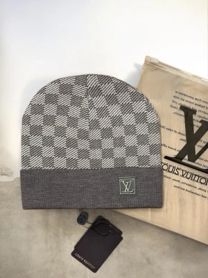 Grå Rutig Mössa | Grå | One Size - Designer mössa i rutigt mönster, grå  Storlek: One size  Mössa med Damier-mönster och logodetalj. Vanlig modell för vardagsbruk och perfekt för kallare årstider. Skickas inom 24 h!