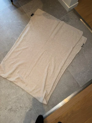 Beige halsduk från Lisa Yang - Säljer en stilren beige halsduk från Lisa Yang i mjukt material. Halsduken är rektangulär och har en diskret svart etikett med logga i ena hörnet. Perfekt för dig som gillar minimalistisk och clean stil. 100% Cashmire 2499:- nypris