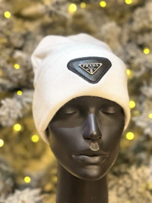 Vit mössa - . Mössan har en enkel och stilren design, perfekt för dig som gillar exklusiva accessoarer. Tillverkad i mjukt material som sitter skönt på huvudet.