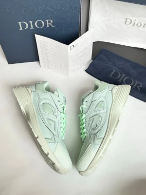 Mintgröna Dior B30 sneakers - Säljer ett par exklusiva Dior B30 sneakers i en fräsch mintgrön färg. Skorna har en chunky sula, rund tå och är tillverkade i en mix av mesh och skinn med tydliga Dior-loggor på sidan och tungan. Matchande mintgröna skosnören ger en clean och modern vibe.