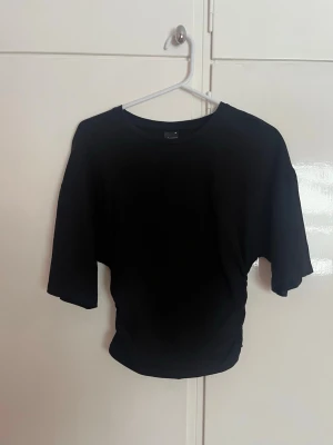 Soft touch figurformad T-shirt- Gina Tricot - En stilren svart t-shirt med rund hals och halvärm. Perfekt till jeans eller kjol för en enkel och clean look. T-shirten har en figurformad stil och är tillverkad i mjukt material som känns skönt mot huden.