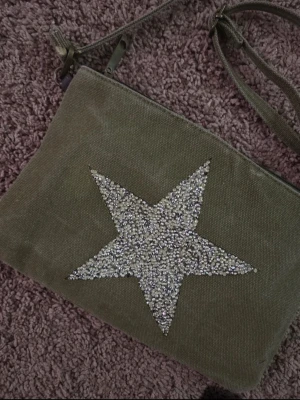 y2k väska med rhinestone-stjärna - Snygg väska med 2000s tals vibes med axelrem och en stor glittrig stjärna framtill. Den är köpt second hand men är i väldigt bra skick!