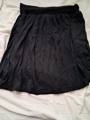 Svart kortkjol från Dedicated XS - Svart kortkjol från Dedicated i mjukt och lätt material av Tencel. Kjolen har en enkel, klassisk design med resår i midjan och faller snyggt. Perfekt att matcha med en crop top eller hoodie.