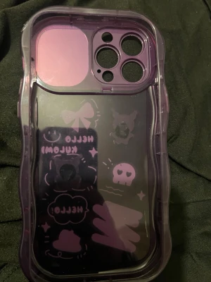 Lila Kuromi mobilskal med spegel - Sött lila mobilskal med Kuromi-motiv och 3D-dekorationer. Skalets baksida har tecknade figurer, stjärnor, rosett och texten 'Hello Kuromi'. Kameraskyddet har inbyggd spegel och kan skjutas åt sidan. Tillverkat i tålig plast, perfekt för dig som gillar kawaii-stil.