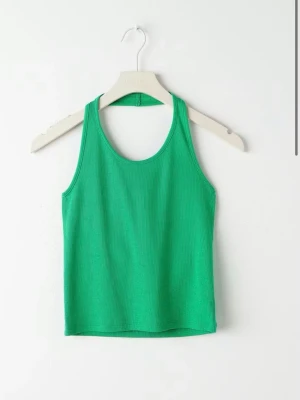 Grön ribbad linnetopp - En enkel och fräsch grön linnetopp med ribbad struktur. Toppen är ärmlös och har en klassisk rund halsringning. Perfekt för varma dagar och lätt att matcha med olika stilar.