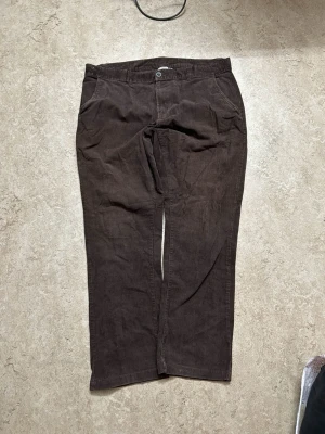 Bruna manchesterbyxor med raka ben - Snygga bruna manchesterbyxor med klassisk rak passform och normal midja. Byxorna har fickor fram och bak, samt stängs med knapp och dragkedja. Perfekta för dig som gillar retrostil och mjukt material.