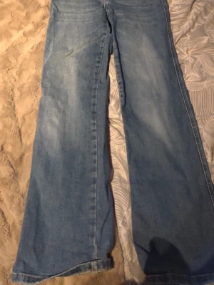 Blå wide jeans från 157 - Säljer ett par ljusblå wide jeans från 157 med klassisk femficksmodell och hög midja. Jeansen har en avslappnad passform med breda ben och är tillverkade i bomull. Perfekta för en chill och trendig look.