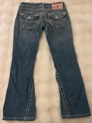 True Religion fat stitch bootcut jeans - Ultra low waist. De är för små för mig så har tyvärr ingen bild på. Midjemått rakt över är 36cm. Innerbenslängd 70cm och dragkedja 6cm