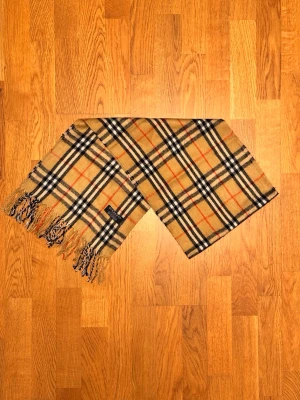 Beige Burberry halsduk - Säljer en beige halsduk från Burberry. Halsduken är gjord i 100% lamull och är i fint skick. Var inte rädd för frågor. Priset går ej att diskutera!