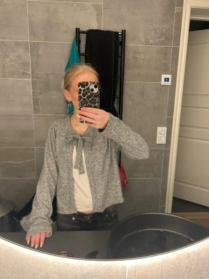 Grå kofta med knyt - Kofta med knyte i fram. Säljer för att jag inte använder. Den är köpt från lager 157 i storlek XS. Kostade 150kr som ny.