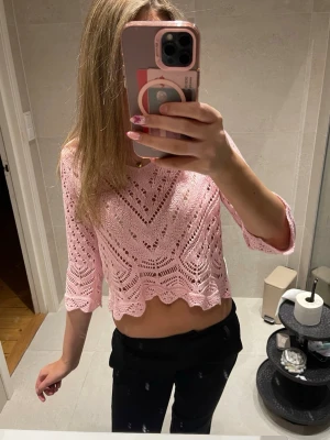 Rosa virkad croppad topp - Söt ljusrosa virkad topp med trekvartsärm och vågig nederkant. Croppad modell med snyggt hålmönster och lätt boho-vibe. Perfekt att styla med jeans eller kjol för en trendig look.