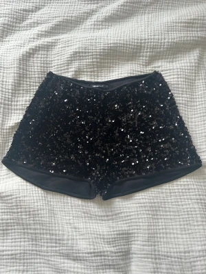 Svarta paljettshorts - Glittriga svarta shorts från Gina Tricot täckta med paljetter. Så snygga o passar perfekt till fest eller till fint! Använda endast en gång. 