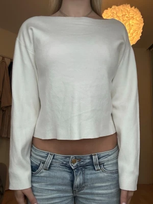 Vit croppad långärmad tröja - Säljer en enkel och stilren vit croppad tröja med långa ärmar och rak passform. Tröjan har en bred, båtringad halsringning. Perfekt till jeans eller kjol för en clean look. 